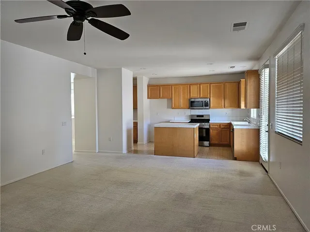 a room with stainless steel appliances kitchen island granite countertop a stove top oven a sink a dining table and chairs