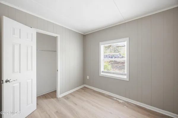 a view of an empty room with closet and a window