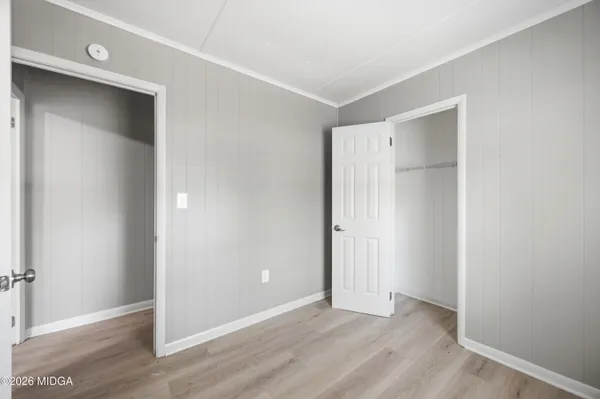an empty room with wooden floor & closet area