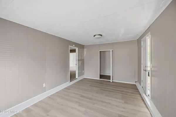 a view of an empty room with wooden floor and closet