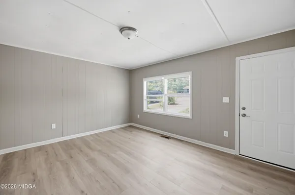 an empty room with wooden floor and windows