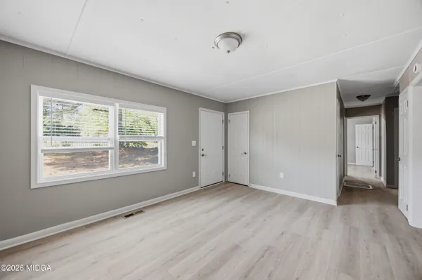a view of an empty room with wooden floor and a window
