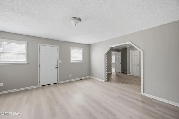 a view of an empty room with wooden floor and a window