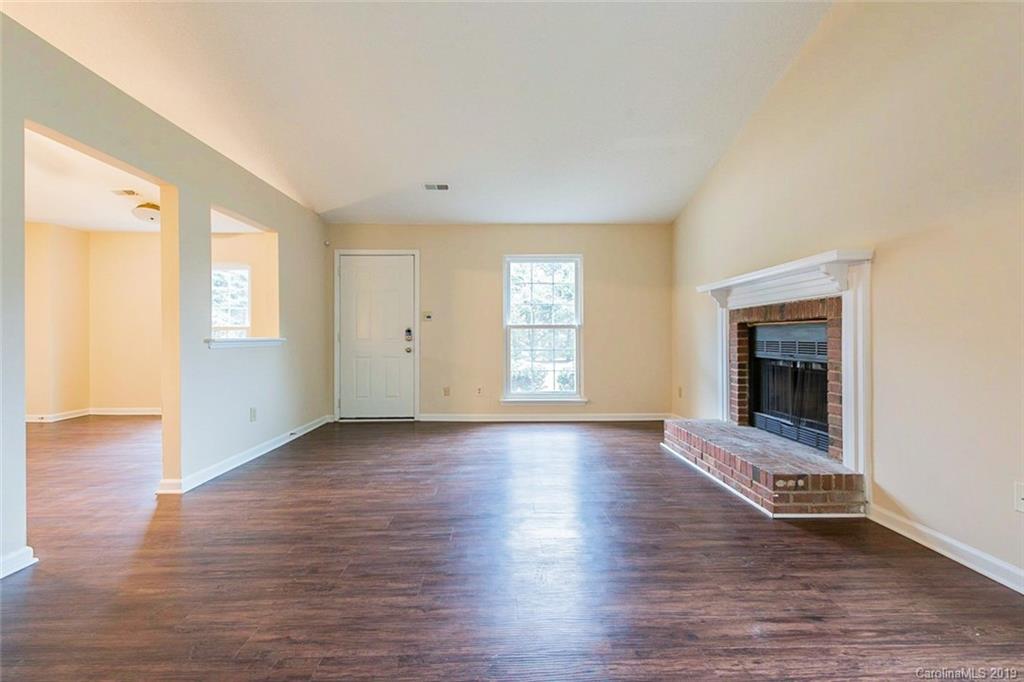 5919 Hunters Crossing Lane Charlotte, NC 28215 - Photo 3 of 14 an empty room with wooden floor fireplace and windows
