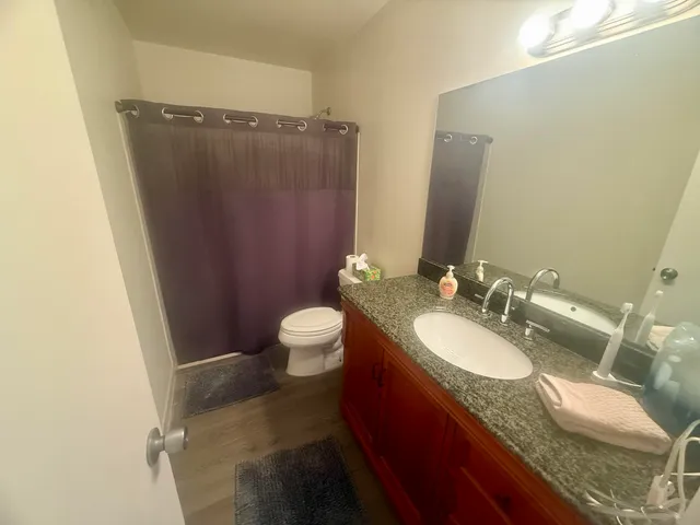 a bathroom with a granite countertop sink toilet and shower