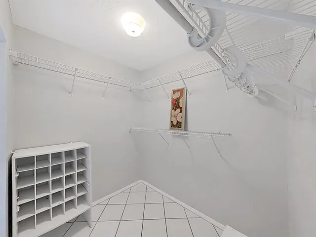 a view of an empty room with window and chandelier fan
