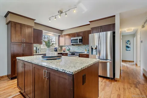 a kitchen with stainless steel appliances granite countertop a refrigerator a sink a stove and island