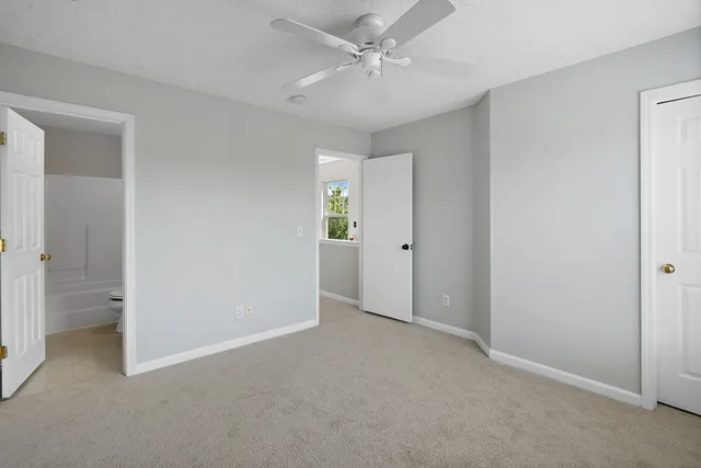 an empty room with a fan & a window