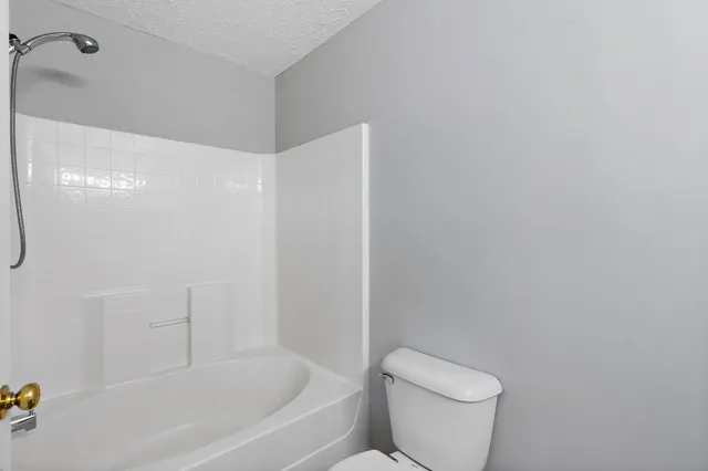 a white toilet sitting next to a bath tub