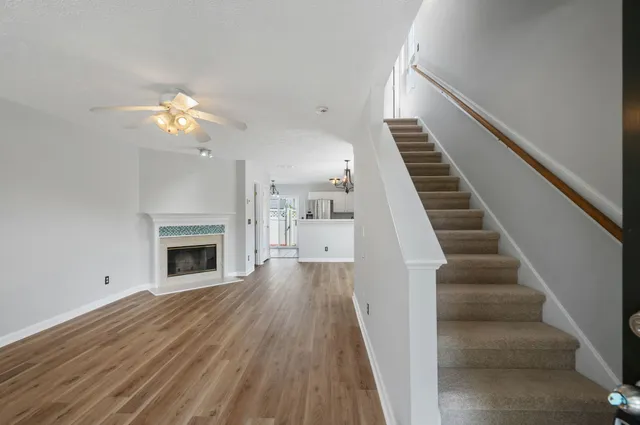 a view of a livingroom with wooden floor a ceiling fan and staircase