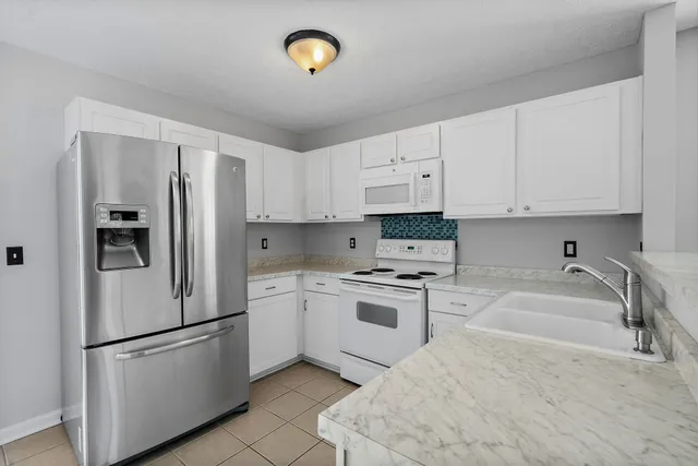 a kitchen with stainless steel appliances granite countertop a refrigerator a stove a sink and white cabinets