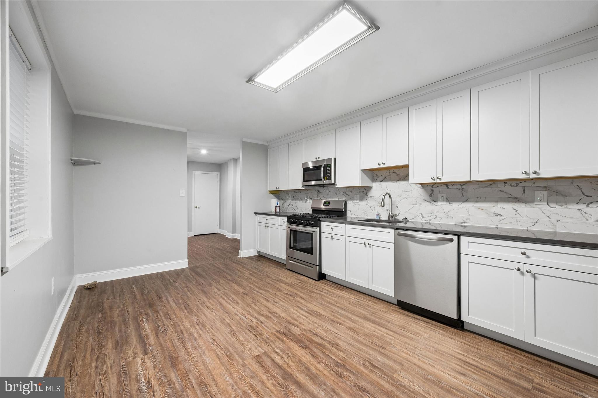 6129 Spruce Street Philadelphia, PA 19139 - Photo 7 of 18 a kitchen with granite countertop wooden floors stainless steel appliances and white cabinets