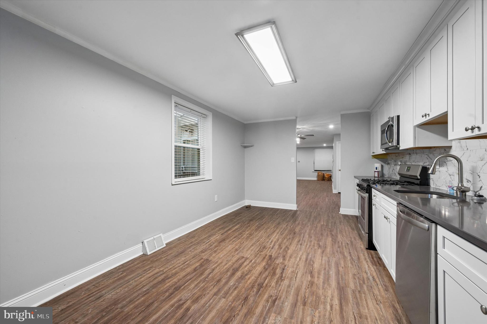 6129 Spruce Street Philadelphia, PA 19139 - Photo 8 of 18 a view of a kitchen with a sink wooden floor and stainless steel appliances