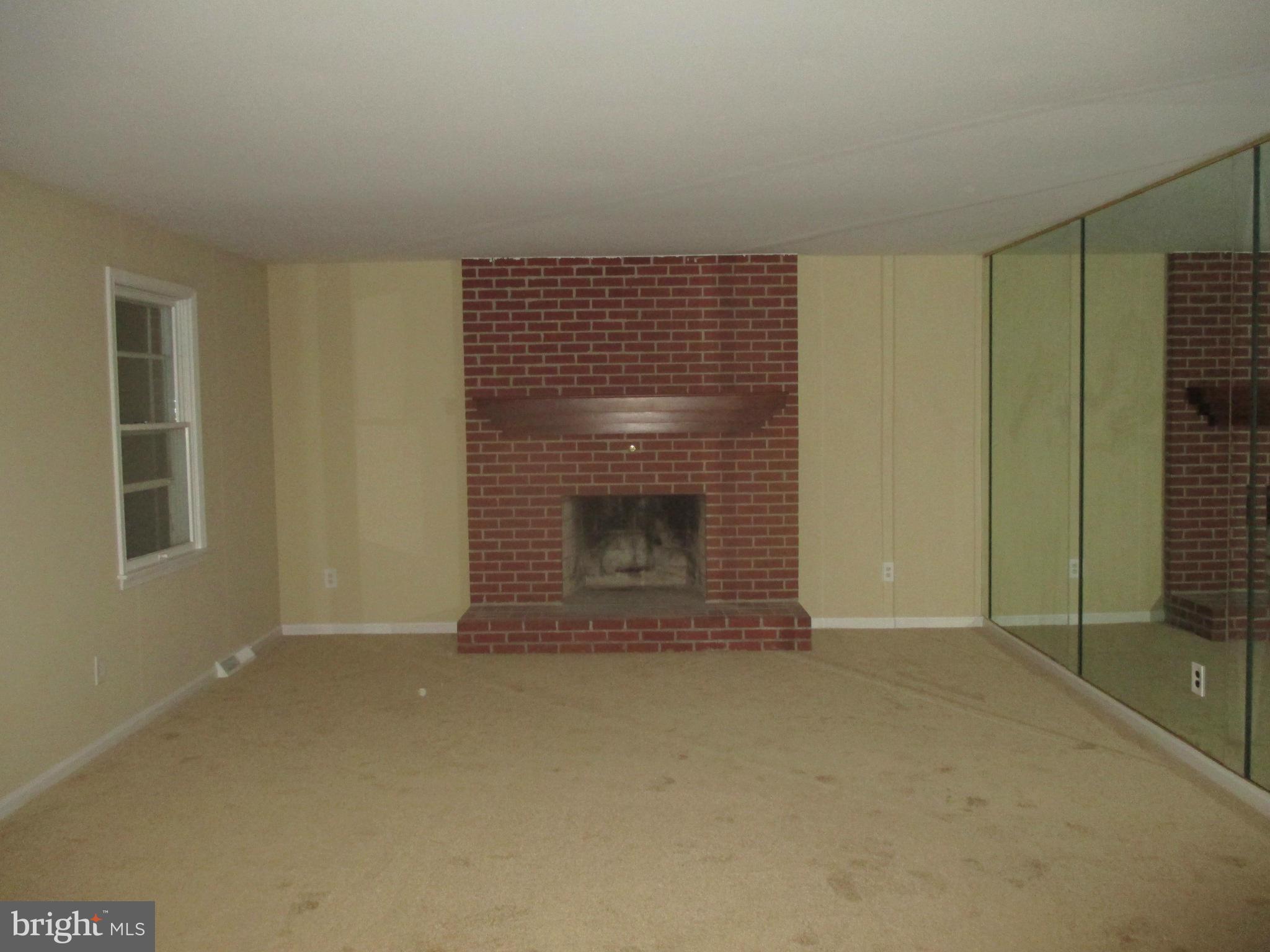 19706 Trunk Road White Hall, MD 21161 - Photo 9 of 19 a view of an empty room with a fireplace and a window