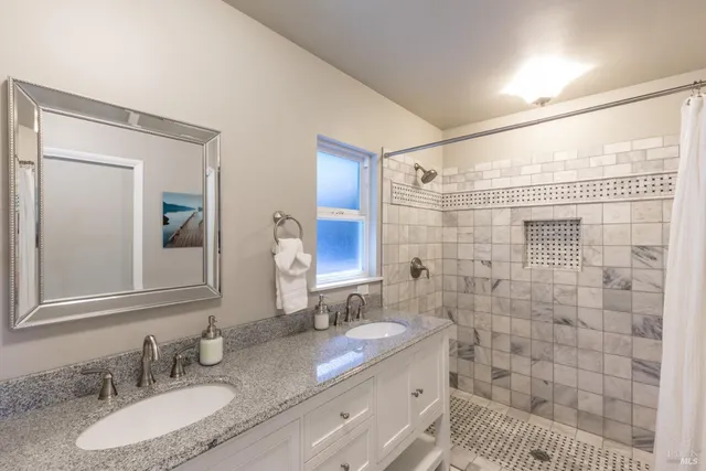 a bathroom with a granite countertop sink a mirror and a shower