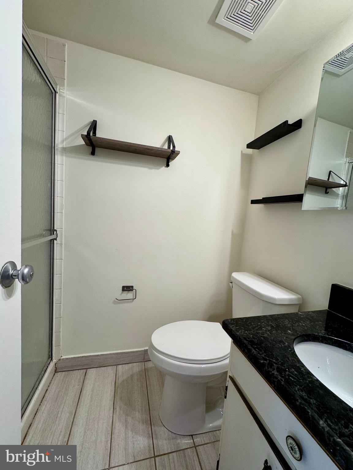 2247 Castle Rock Square, Unit 1B Reston, VA 20191 - Photo 24 of 26 a bathroom with a granite countertop toilet a sink and a mirror