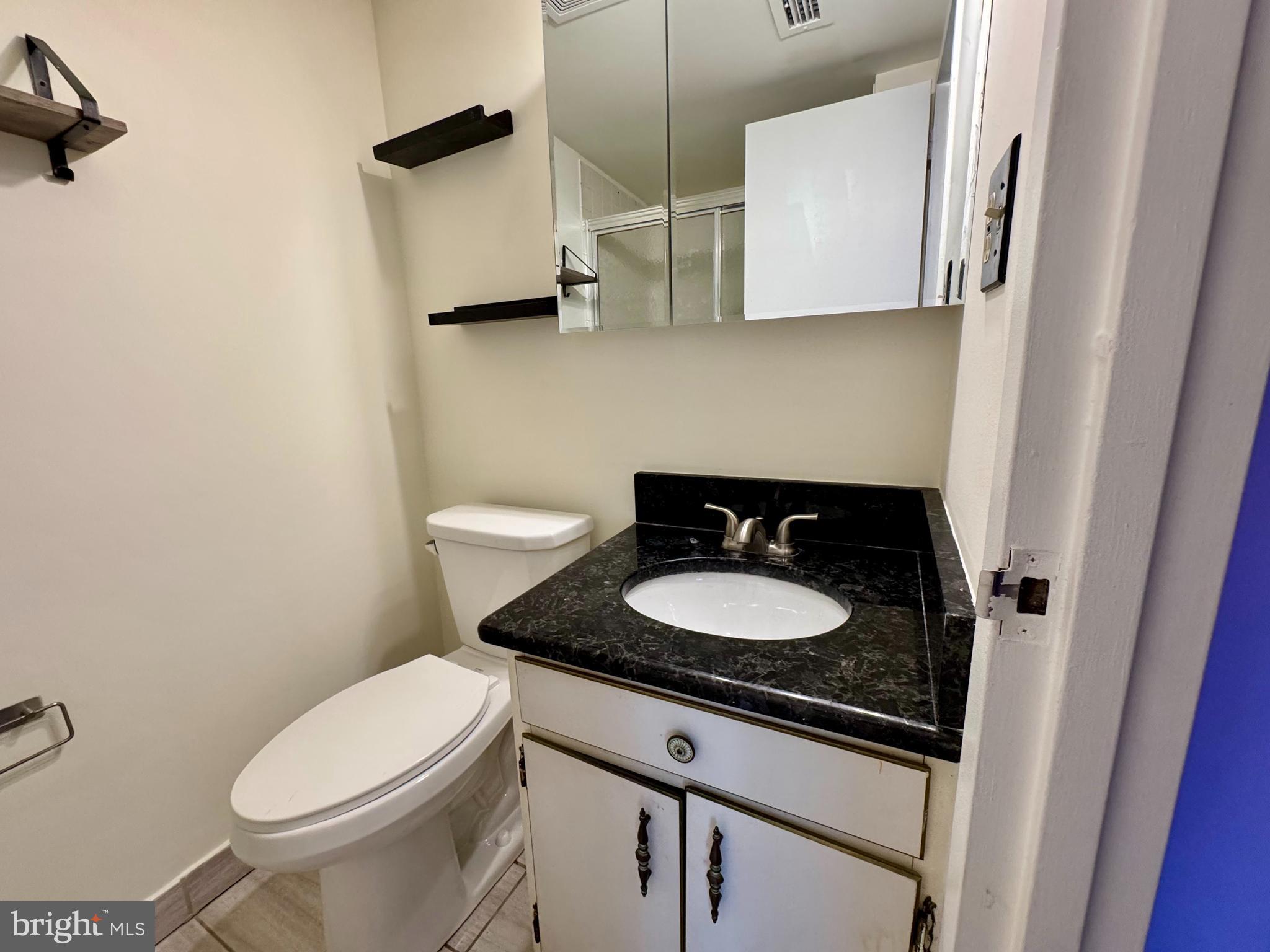 2247 Castle Rock Square, Unit 1B Reston, VA 20191 - Photo 25 of 26 a bathroom with a granite countertop sink and a toilet