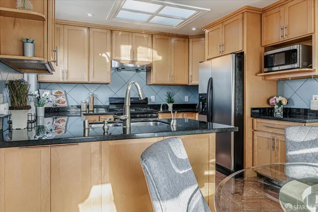 a kitchen with stainless steel appliances granite countertop a refrigerator a stove top oven a sink and cabinets