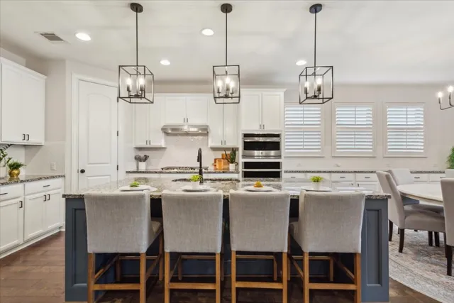 a kitchen with a dining table chairs and white cabinets