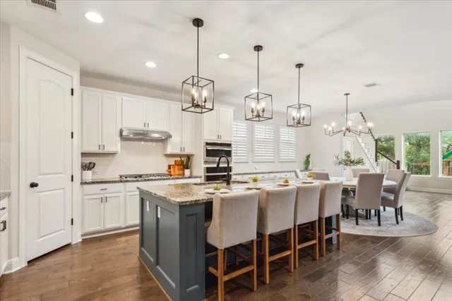 a kitchen with stainless steel appliances granite countertop a stove a sink dishwasher a stove a dining table and chairs with wooden floor