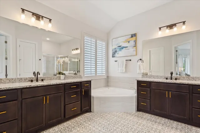 a spacious bathroom with a granite countertop double vanity sink a mirror and a bathtub