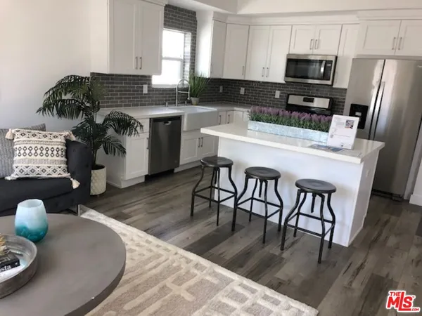 a kitchen with stainless steel appliances granite countertop a sink a stove a kitchen island with chairs and wooden floor