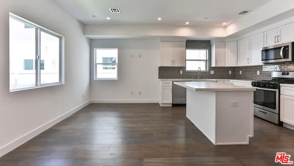 a kitchen with stainless steel appliances granite countertop a sink a stove a refrigerator cabinets and a window