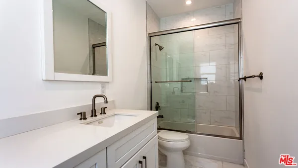 a bathroom with a shower sink vanity mirror and toilet