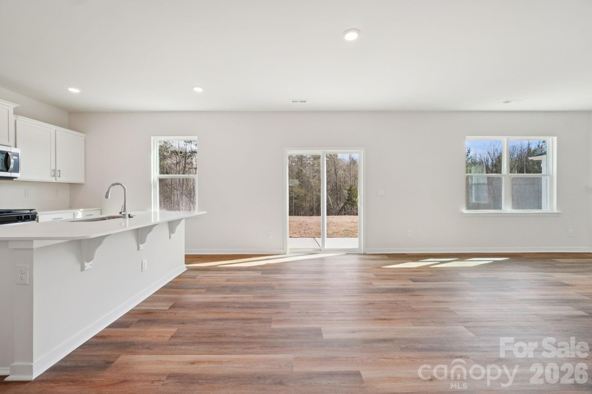 4559 Harris Elliot Road Lincolnton, NC 28092 - Photo 3 of 36 a large white kitchen with granite countertop a stove top oven a sink with wooden floors and cabinets