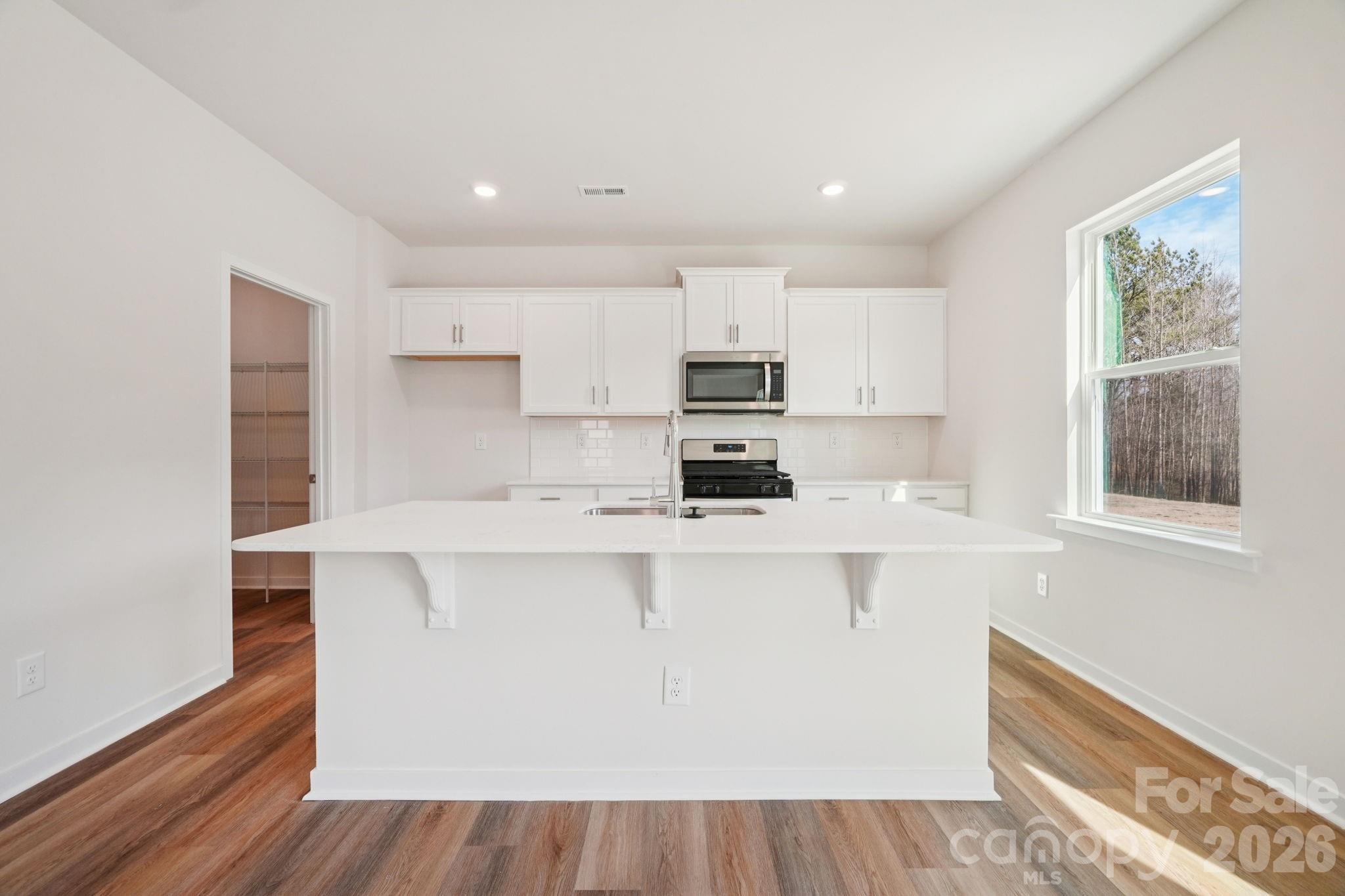 4559 Harris Elliot Road Lincolnton, NC 28092 - Photo 7 of 36 a kitchen with kitchen island a stove a sink a refrigerator and cabinets