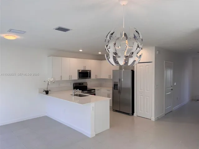 a kitchen with stainless steel appliances a stove a refrigerator and a chandelier