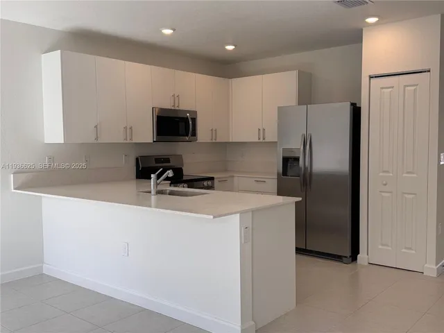 a kitchen with stainless steel appliances granite countertop a refrigerator a sink a stove a microwave and a refrigerator