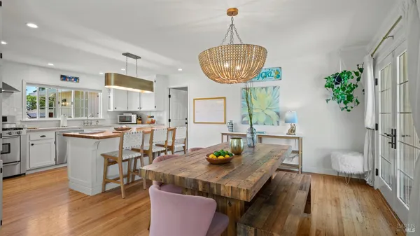 a kitchen with kitchen island stainless steel appliances a table chairs and wooden floor
