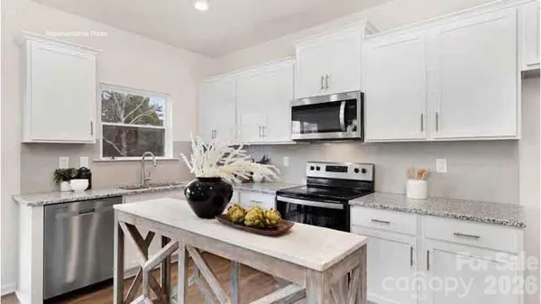a kitchen with stainless steel appliances granite countertop a stove a sink a microwave a refrigerator and cabinets