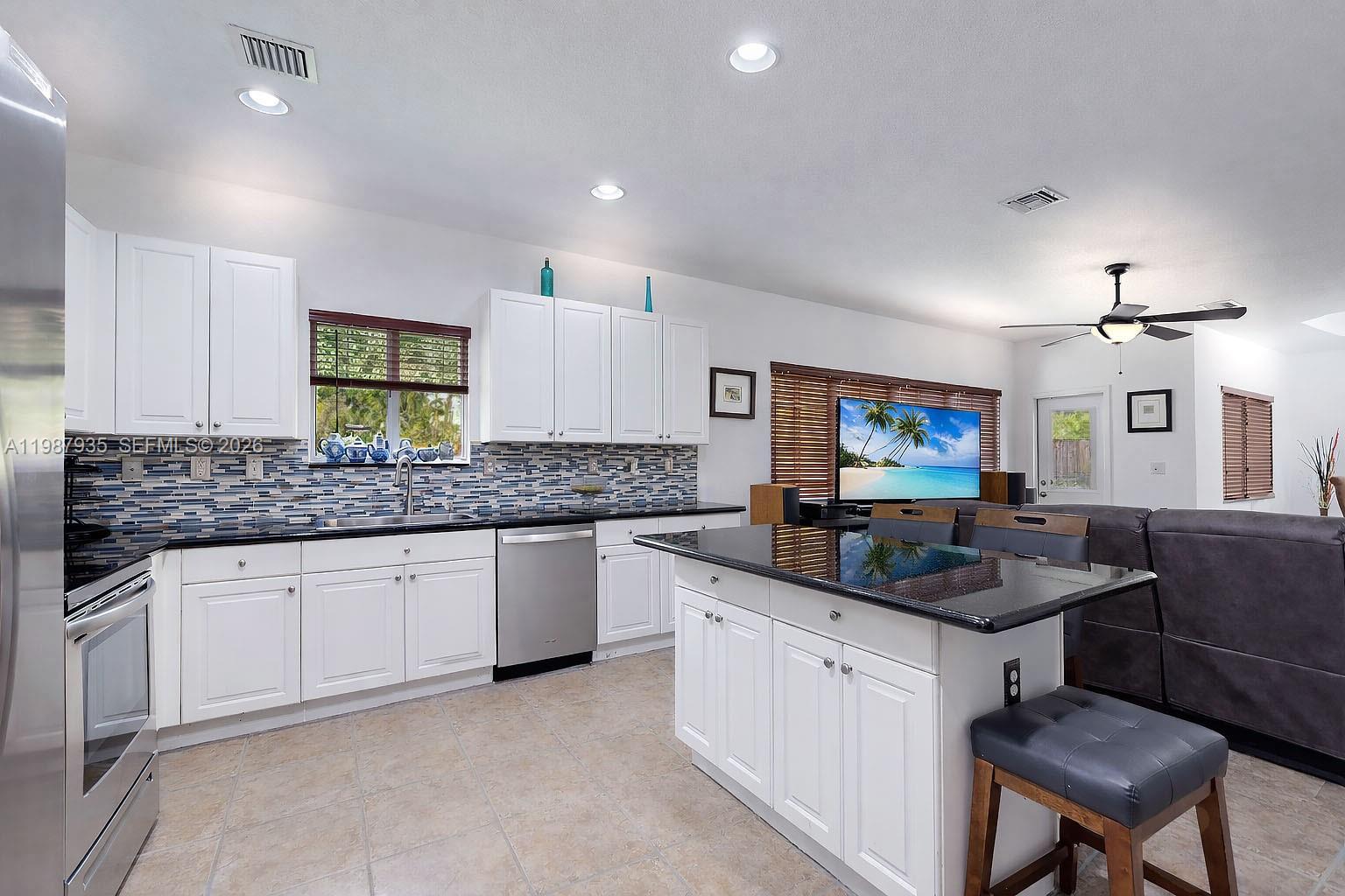 16479 Southwest 50th Terrace Miami, FL 33185 - Photo 19 of 51 a kitchen with granite countertop a sink and white cabinets