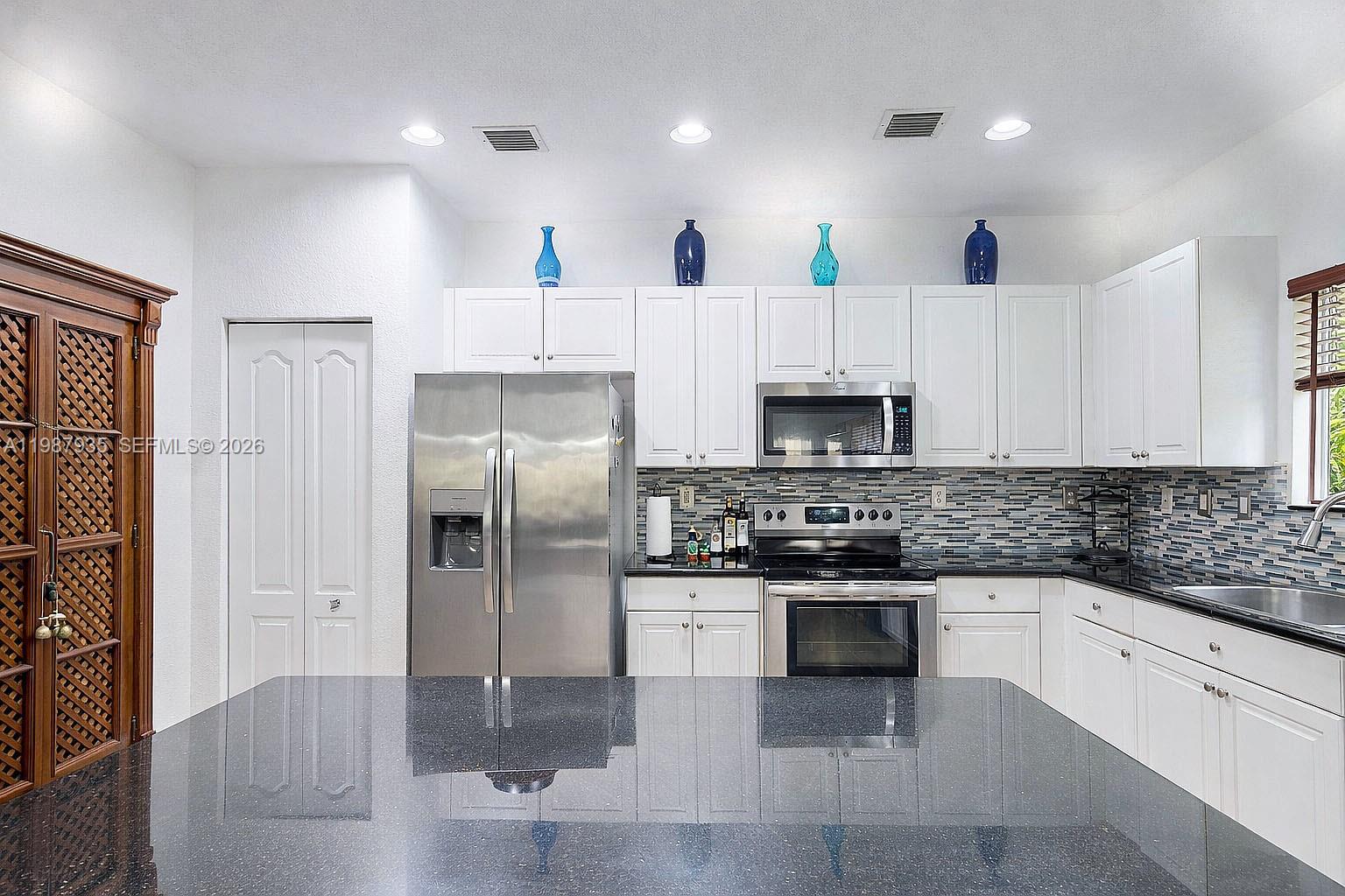 16479 Southwest 50th Terrace Miami, FL 33185 - Photo 20 of 51 a kitchen with stainless steel appliances granite countertop a stove a refrigerator and a sink