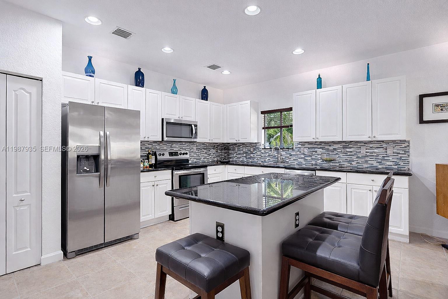 16479 Southwest 50th Terrace Miami, FL 33185 - Photo 21 of 51 a kitchen with stainless steel appliances granite countertop a sink a stove a refrigerator and a refrigerator