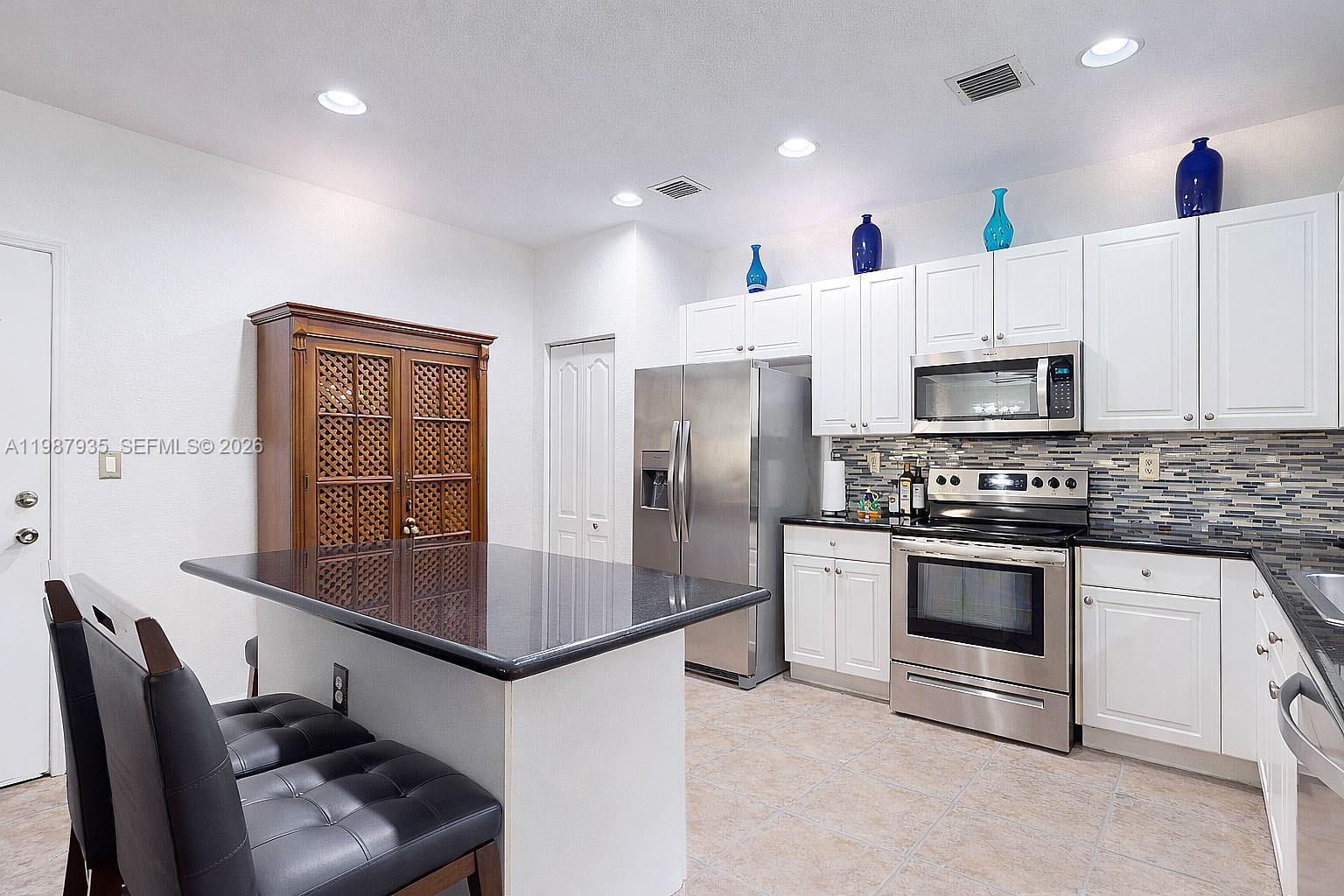 16479 Southwest 50th Terrace Miami, FL 33185 - Photo 23 of 51 a kitchen with kitchen island a stove a sink and a refrigerator