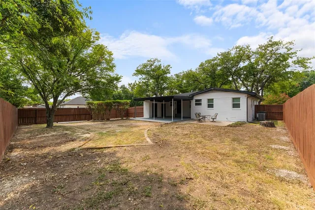 a view of a house with a yard and large tree