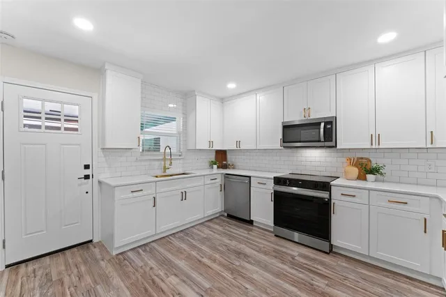 a kitchen with white cabinets stainless steel appliances and sink