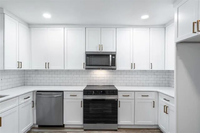 a kitchen with granite countertop white cabinets and stainless steel appliances
