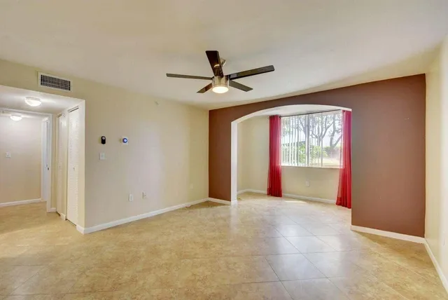 a view of a livingroom with a chandelier fan and a kitchen space