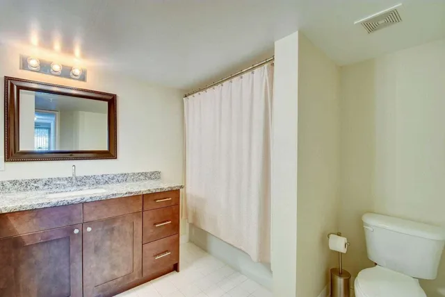 a bathroom with a granite countertop sink and a mirror with toilet