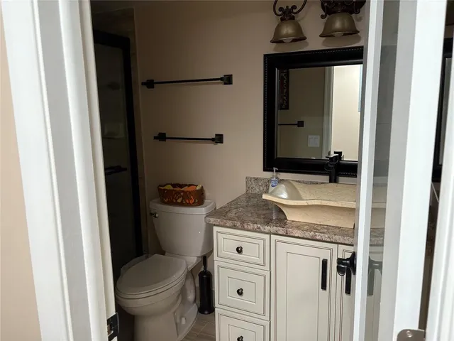 a bathroom with a granite countertop sink and a toilet