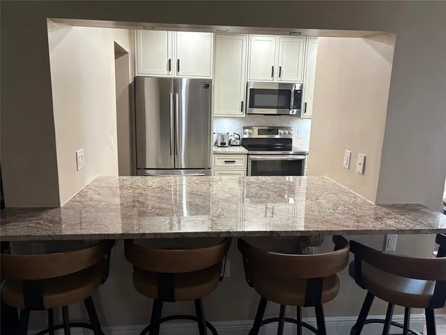 a kitchen with granite countertop a refrigerator and a stove top oven
