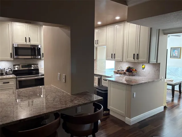 a kitchen with granite countertop a stove a sink and a microwave