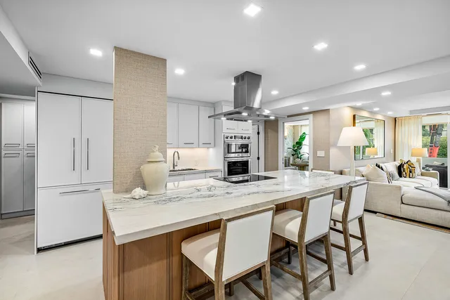 a kitchen with stainless steel appliances kitchen island granite countertop a table chairs sink and wooden cabinets