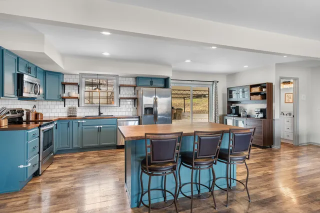 a dining hall with stainless steel appliances kitchen island granite countertop a dining table and chairs