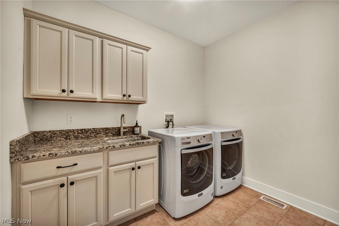 11295 Sutton Place Chardon, OH 44024 - Photo 25 of 50 Laundry area with washing machine and dryer, light tile patterned floors, and cabinet space