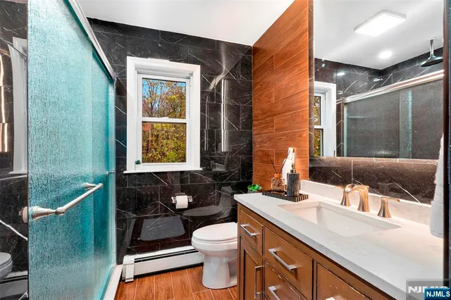 a bathroom with a granite countertop sink toilet a mirror and shower